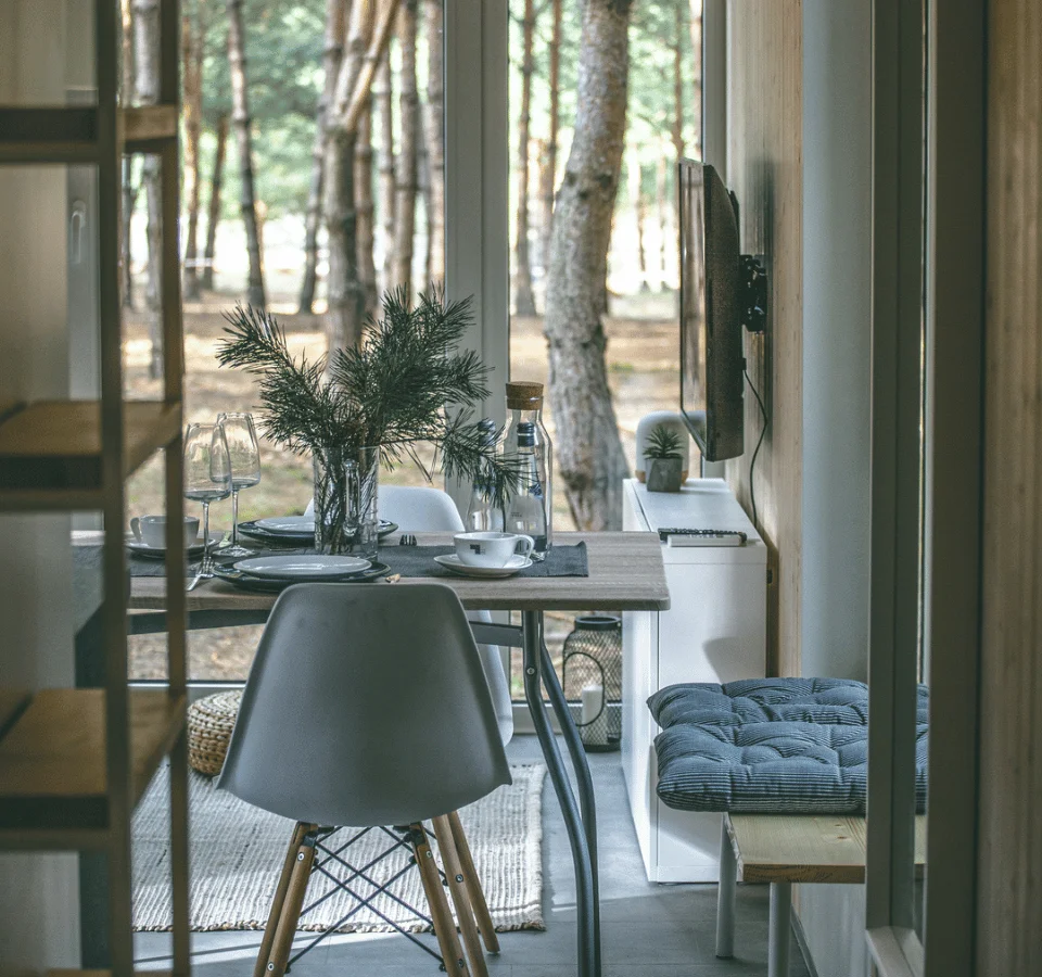 Tiny house with a view, a set table with cutlery, plates, and plants.