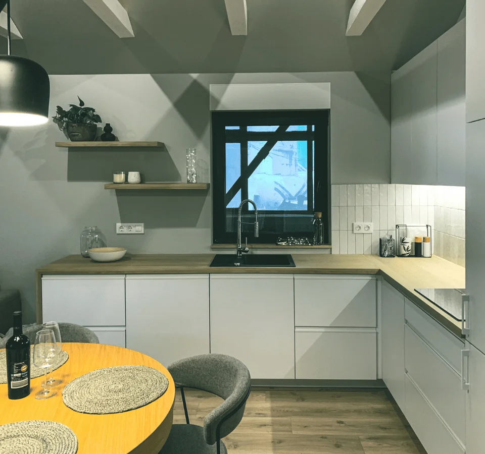 Tiny house stuga kitchen with window and dining table, white cabinets, brown countertop