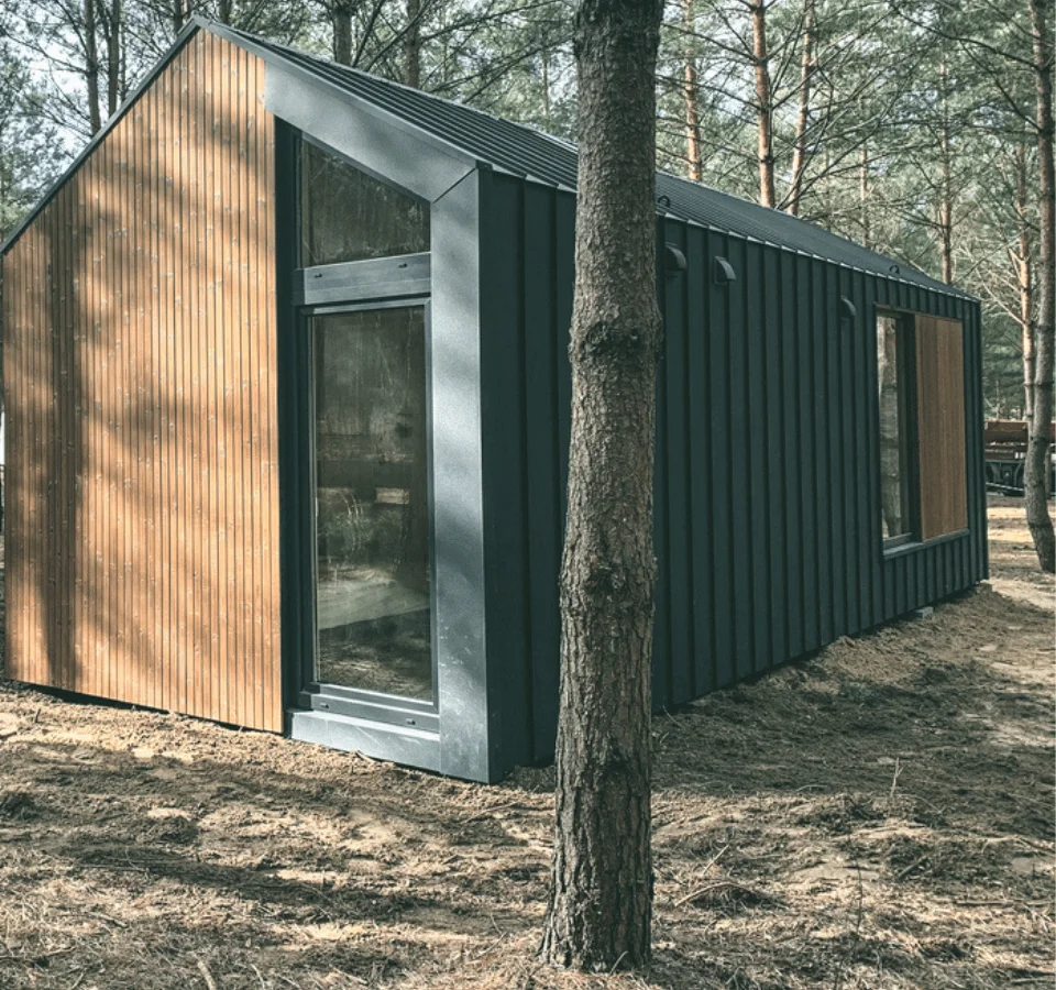 Tiny house in Malmö, back view, with a tree and brown ground.
