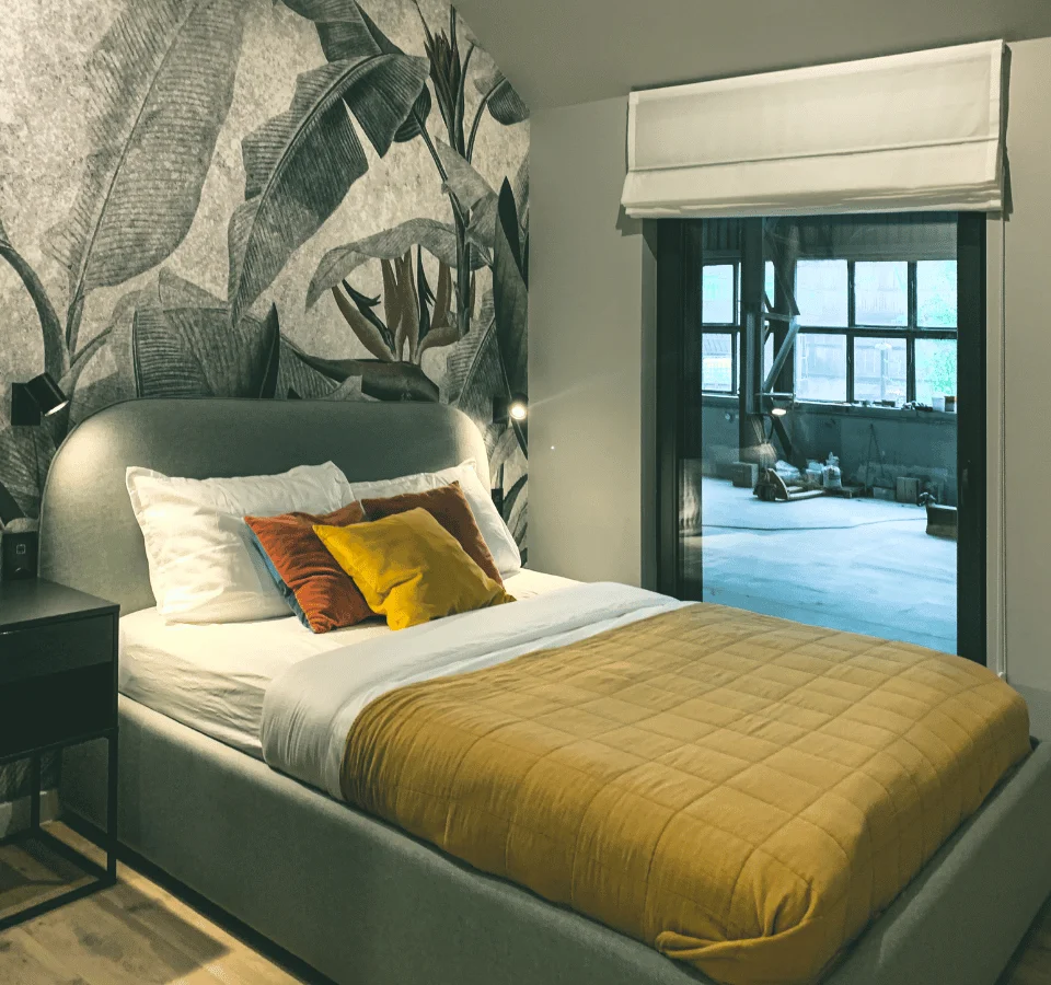 Tiny house stuga bedroom, double bed, yellow blanket, yellow pillow, three pillows, large window