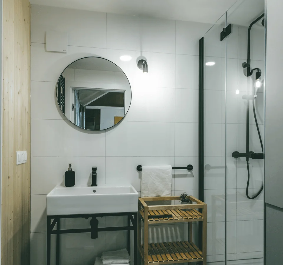 Tiny house bathroom with a mirror, shower cabin, washbasin, and a wooden table. Bathroom of the Tiny House Malmö.