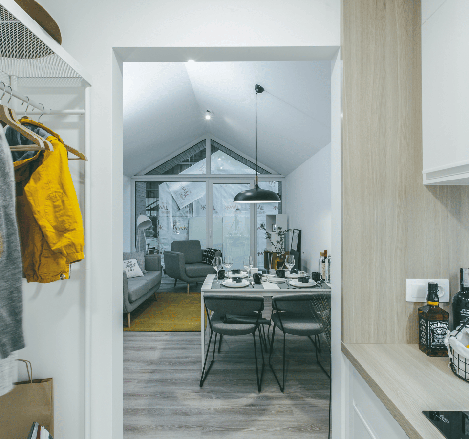 Inside the Malmo+ Tiny House, there is a kitchen and living room with a dining table