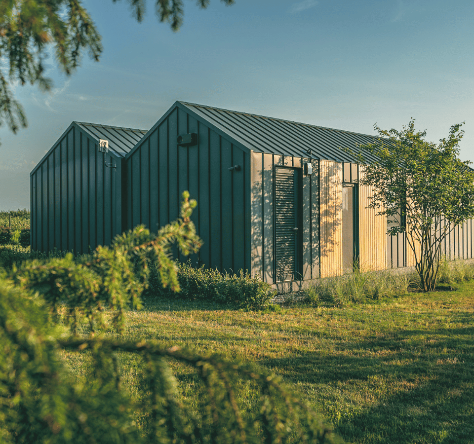 Back view of a modern and luxurious Tiny House, outdoors, grass, trees.
