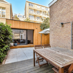 Garden Studio with Wooden Table, Glass Door and Window, Stone Terrace, Green Fence
