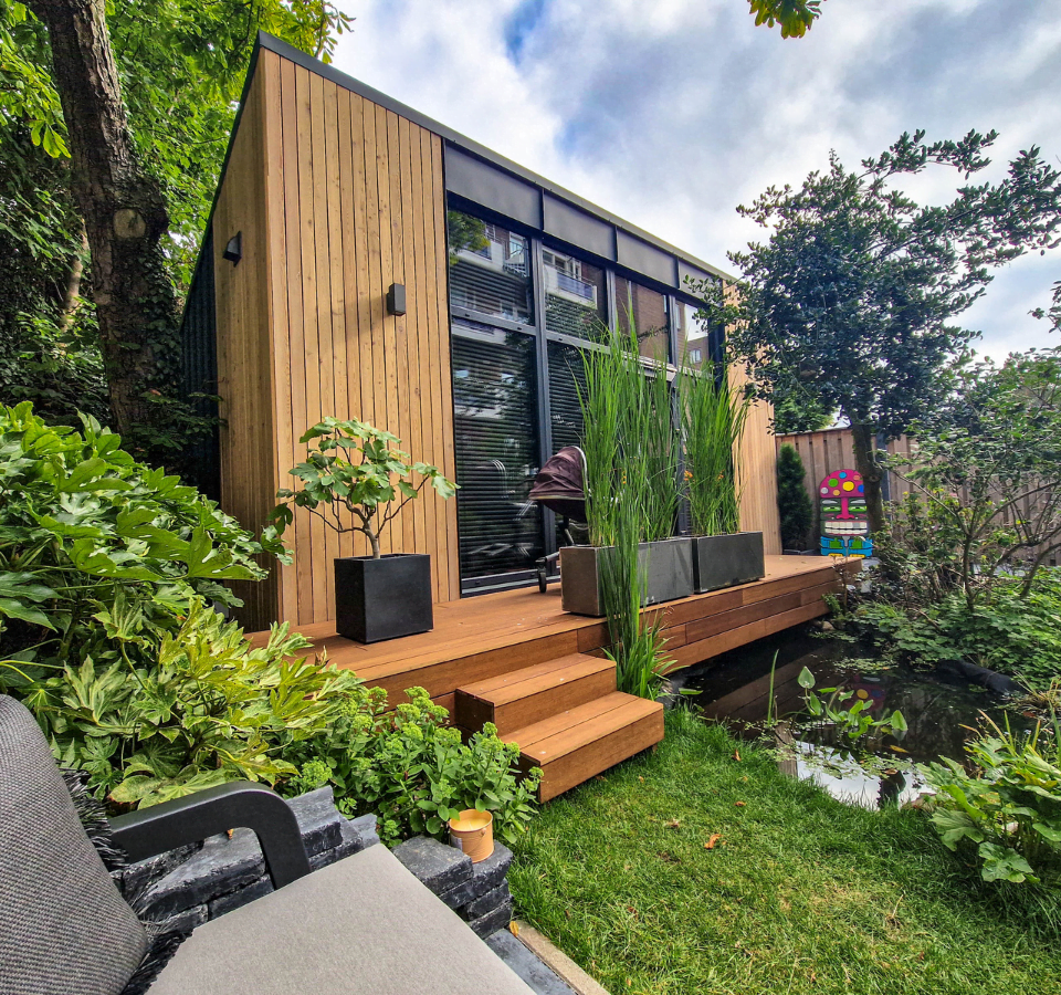 extra groot tuin kantoor, achtertuin, houten terras, grote ramen, oplopend dak, groen gras en planten, vijfer met water