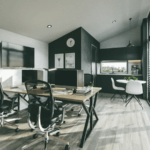 Interior of the garden office, featuring a dining table with chairs, kitchen area, clock, large window with natural light, PVC flooring, and an ascending ceiling