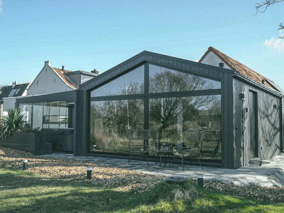 modulair tiny house in de achtertuin, blauwe lucht, stenen pad en gras, zwarte afwerkingen